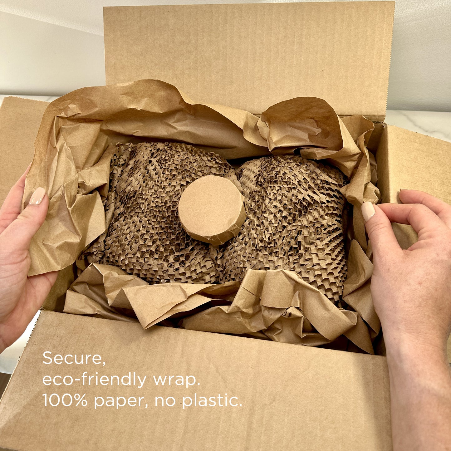 Eco-friendly Lakewood Candles packaging using 100% paper-based materials—no bubble wrap or plastic. Products are securely wrapped in kraft paper and honeycomb paper wrap. A close-up of hands opening a box showcases the sustainable and thoughtful packing process. Highlights zero waste, recyclable, and plastic-free commitment. Emphasizes safe delivery and care for both products and the planet.