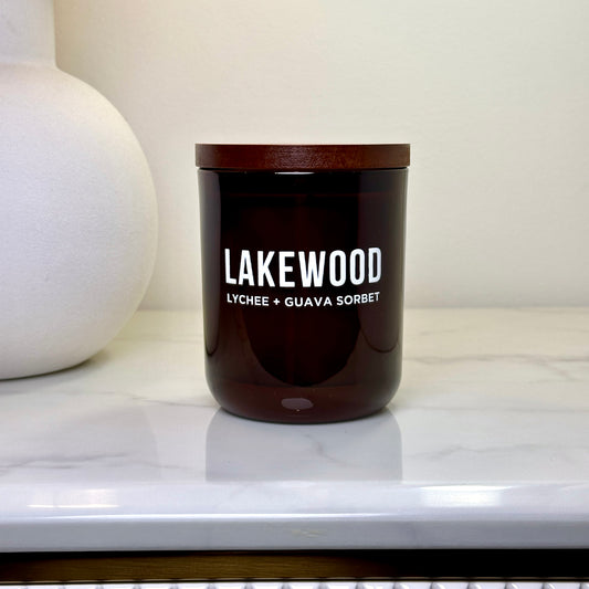 Amber glass candle in minimalist setting, featuring “Lakewood” branding with “Lychee + Guava Sorbet” label and wooden lid. Handmade natural soy wax candle, elegantly styled on a stone countertop, perfect as a gift or home décor item. Part of Lakewood Candles’ clean, customisable and plastic-free packaging collection, crafted in Australia with care.