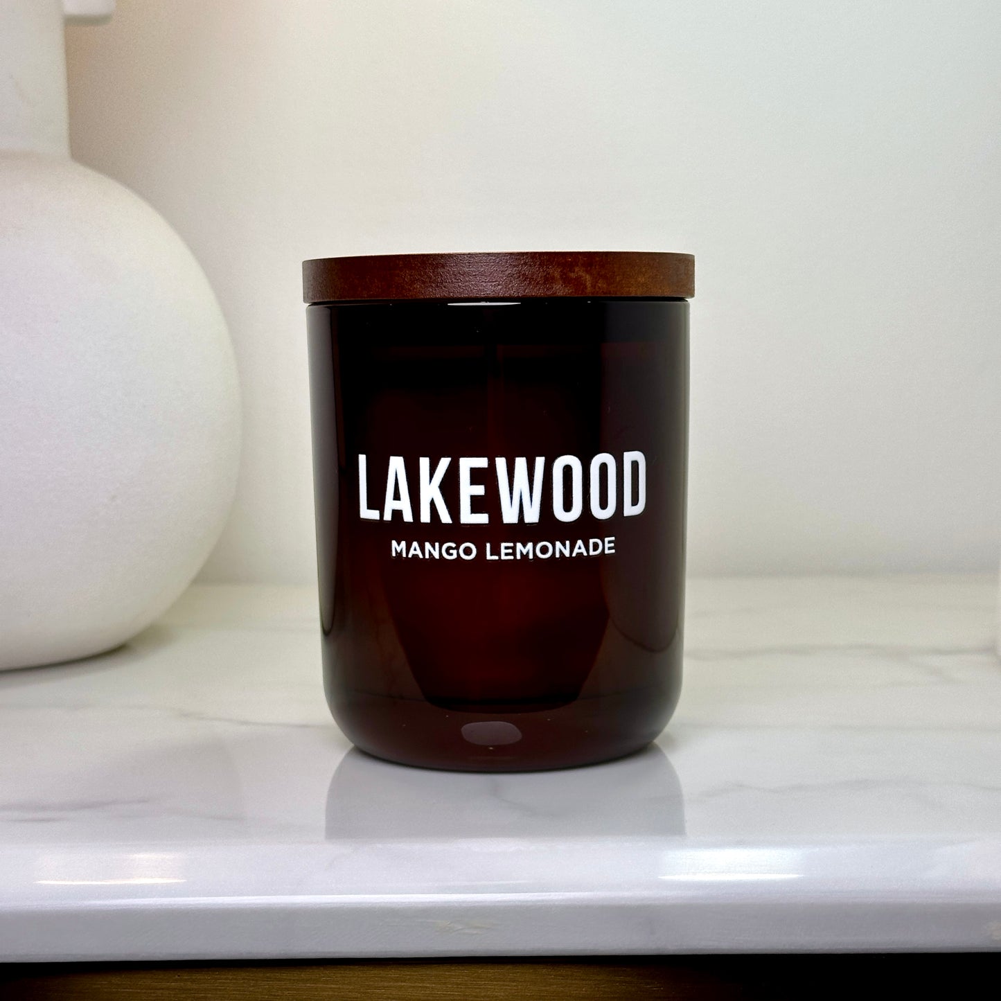 Mango Lemonade Lakewood Candle with wooden lid on a marble surface, minimal background and soft lighting